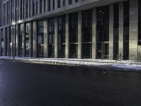 an empty street is covered by ice in front of the office building at night time