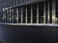 an empty street is covered by ice in front of the office building at night time