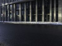 an empty street is covered by ice in front of the office building at night time