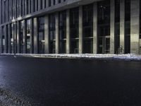 an empty street is covered by ice in front of the office building at night time