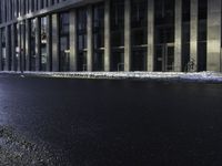 an empty street is covered by ice in front of the office building at night time