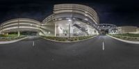 the street is empty as it crosses into the large building at night time in this circular panorama