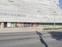 an empty street in front of a museum of nature and science sign on a building