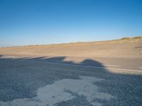 a view of an empty street with shadow of two people on the side of the road