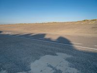 a view of an empty street with shadow of two people on the side of the road