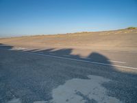 a view of an empty street with shadow of two people on the side of the road