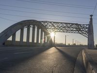 an empty street with the sun coming through the bridge and power lines in the background