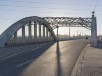 an empty street with the sun coming through the bridge and power lines in the background