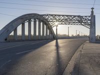 an empty street with the sun coming through the bridge and power lines in the background