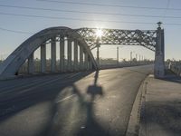 an empty street with the sun coming through the bridge and power lines in the background