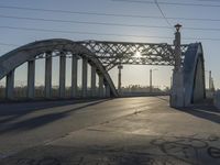 an empty street with the sun coming through the bridge and power lines in the background