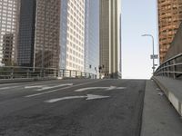 a view of the empty street with several arrows painted on it and tall buildings in the background