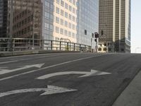 a view of the empty street with several arrows painted on it and tall buildings in the background