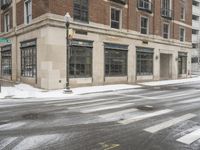 an empty street in front of several buildings covered with snow next to some street signs