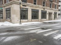 an empty street in front of several buildings covered with snow next to some street signs