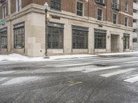 an empty street in front of several buildings covered with snow next to some street signs