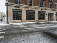 an empty street in front of several buildings covered with snow next to some street signs