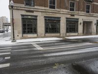 an empty street in front of several buildings covered with snow next to some street signs