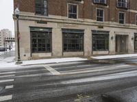 an empty street in front of several buildings covered with snow next to some street signs