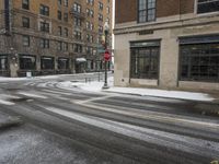 an empty street in front of several buildings covered with snow next to some street signs