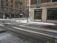 an empty street in front of several buildings covered with snow next to some street signs