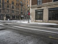 an empty street in front of several buildings covered with snow next to some street signs