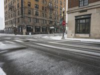 an empty street in front of several buildings covered with snow next to some street signs