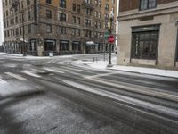 an empty street in front of several buildings covered with snow next to some street signs