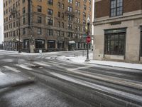 an empty street in front of several buildings covered with snow next to some street signs