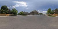 a wide view of an empty street from the sidewalk of a large building with a dome in the background