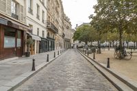 an empty street in a european city with a parked bike on the right side of it