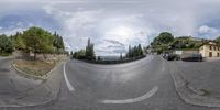 a fisheye lens shows an empty street with cars passing by at night time with a mountain in the distance