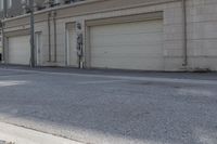 an empty street next to a large garage building with a sign out front that says west side