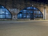 an empty street with graffiti and night sky in background from the corner of a road
