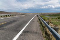 an empty street next to an empty highway with white line going down it and a person standing at the end of a ramp