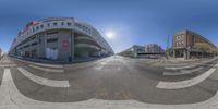 a fish eye shot of the intersection of an empty street and parking garages in the background