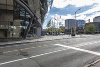 an empty street at an intersection of a street in front of large buildings with glass windows