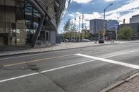 an empty street at an intersection of a street in front of large buildings with glass windows