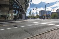 an empty street at an intersection of a street in front of large buildings with glass windows