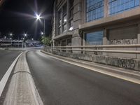 an empty street in a large city with no traffic at night with lights on,