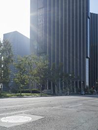 a person walking down a deserted city street with skyscrapers in the background in the daytime