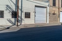 an empty street next to an industrial building in a city intersection with a small black suv parked outside