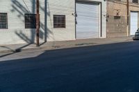 an empty street next to an industrial building in a city intersection with a small black suv parked outside