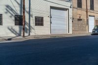 an empty street next to an industrial building in a city intersection with a small black suv parked outside