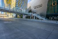 an empty street with several tall buildings in the background and a sign in the middle with an orange marker indicating