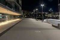 the empty asphalted street is lit up by low light posts and lamps in the background