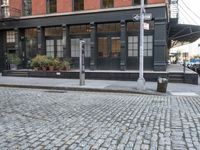 an empty street lined with plants and bushes on the sidewalk outside a building with many windows