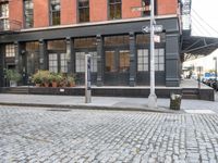 an empty street lined with plants and bushes on the sidewalk outside a building with many windows