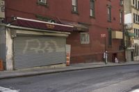 an empty street has a closed garage on the corner near an intersection with parked traffic