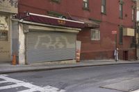 an empty street has a closed garage on the corner near an intersection with parked traffic